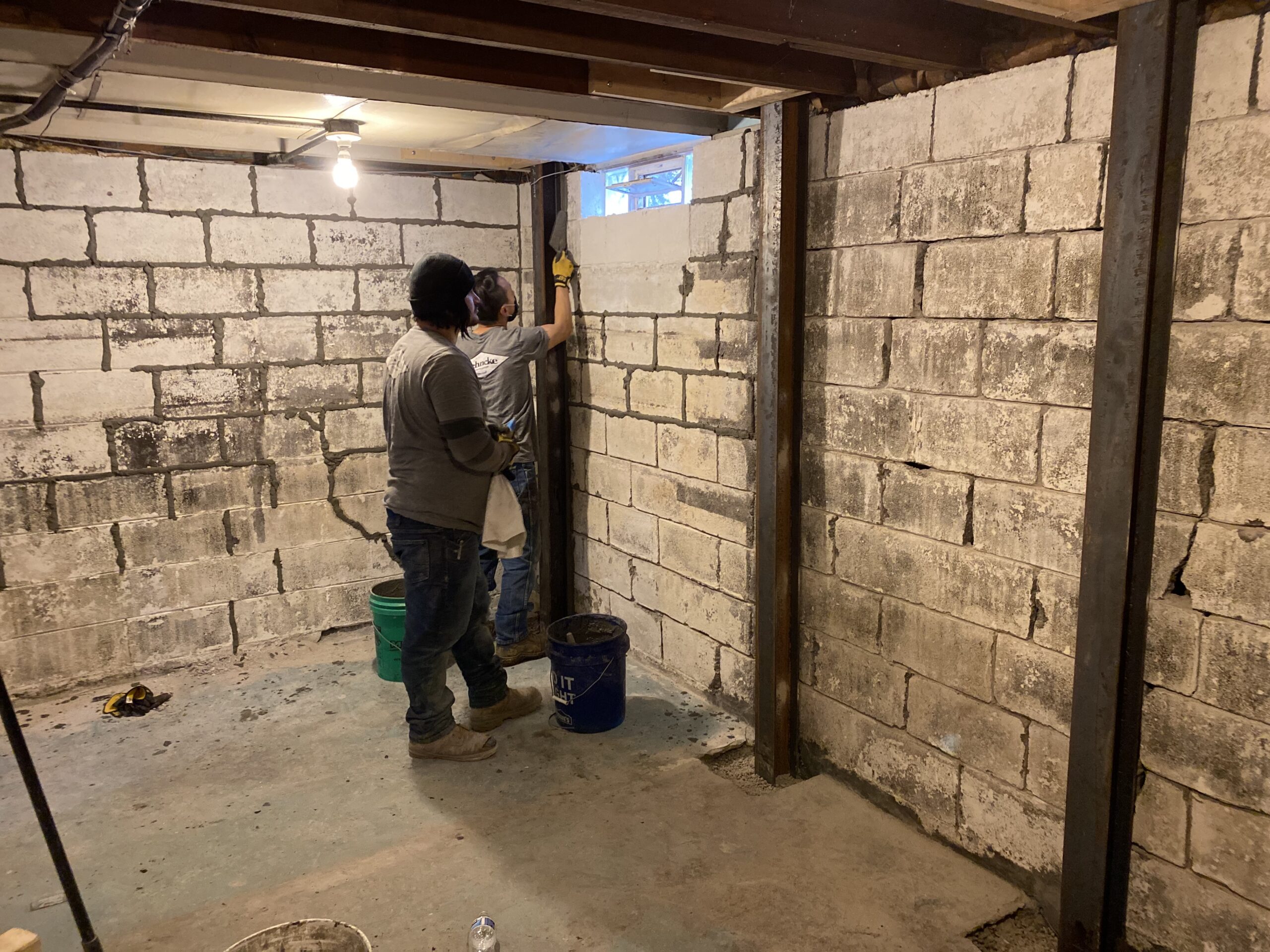 Behncke Construction crew reinforcing a cracked bowing block wall with steel beams