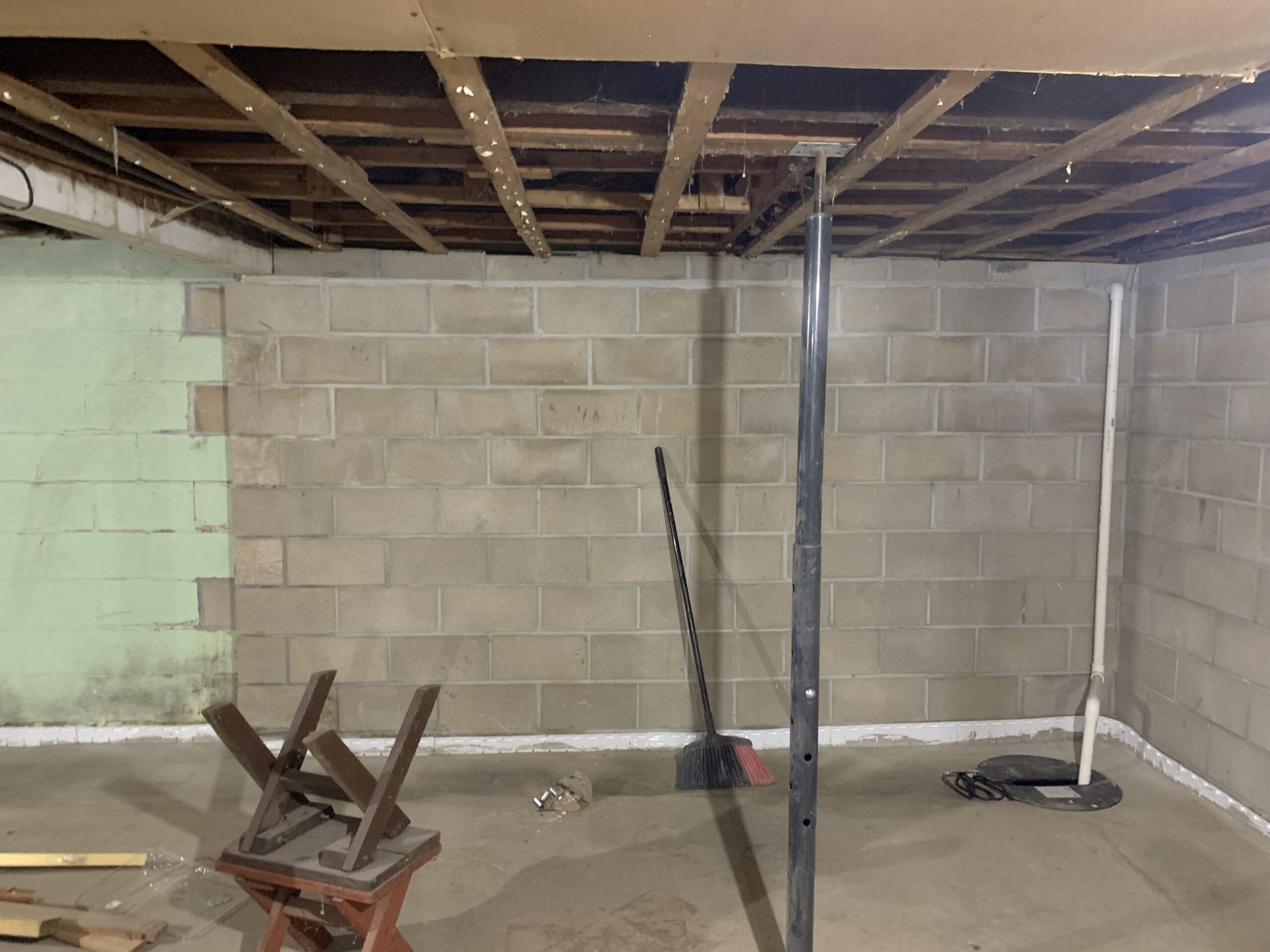 A steel support post carrying the floor structure in a Quad Cities basement