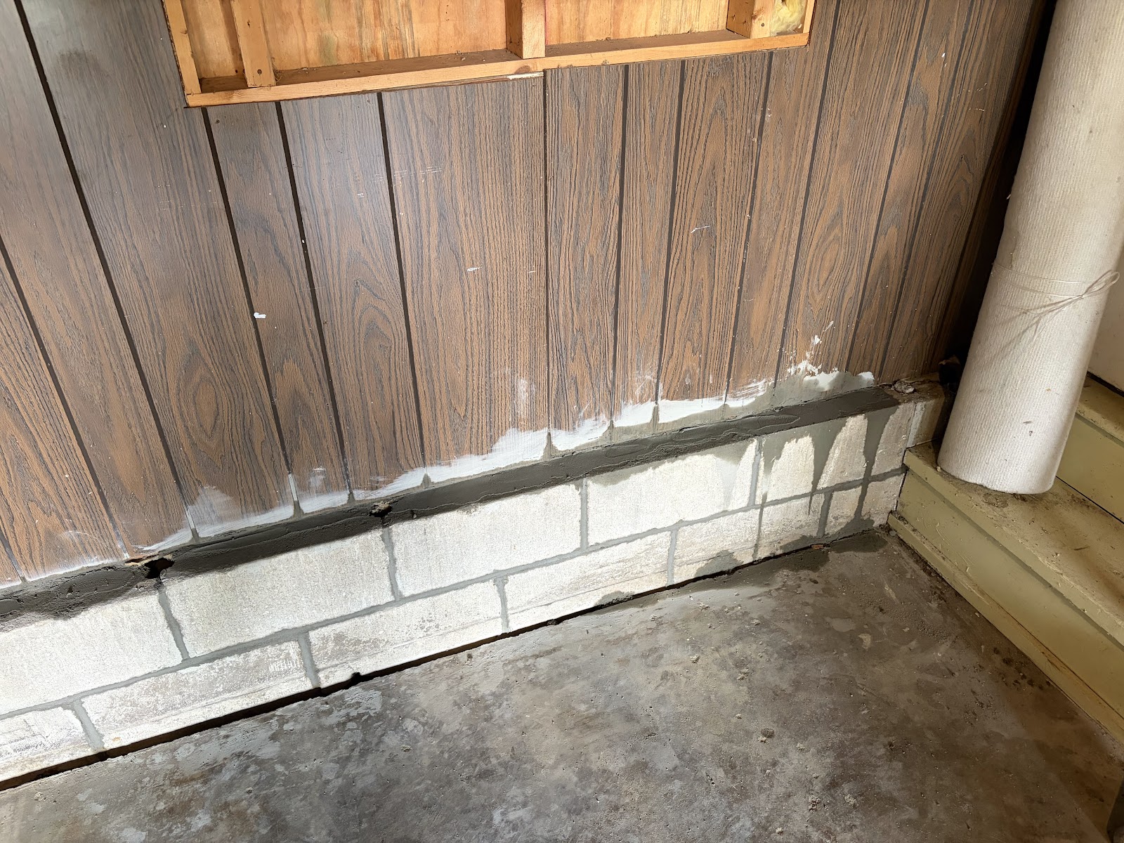 Completed exterior repair — rear garage concrete block wall with fresh mortar joints and a rerouted downspout, Davenport, Iowa