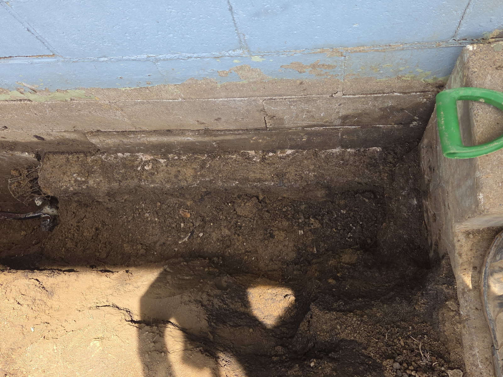 Exterior excavation along the foundation to route the new underground downspout drainage