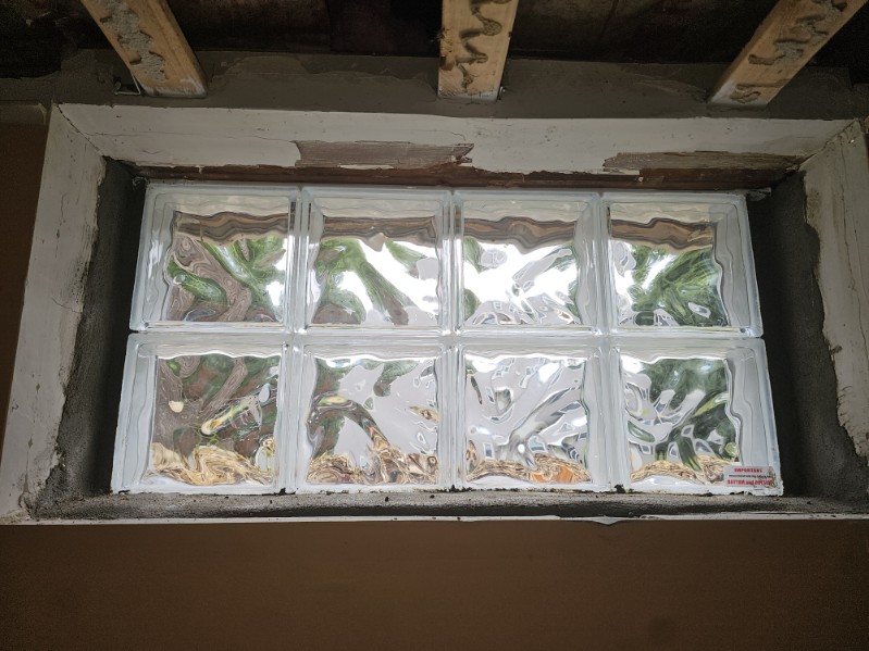 New glass block panels being set into the basement window openings