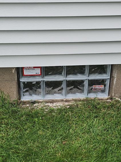 New glass block basement window installed in the foundation below the siding, Davenport, Iowa