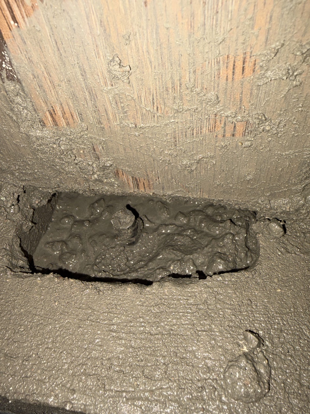 Fresh mortar packed into a concrete block cavity to reinforce the rear garage wall