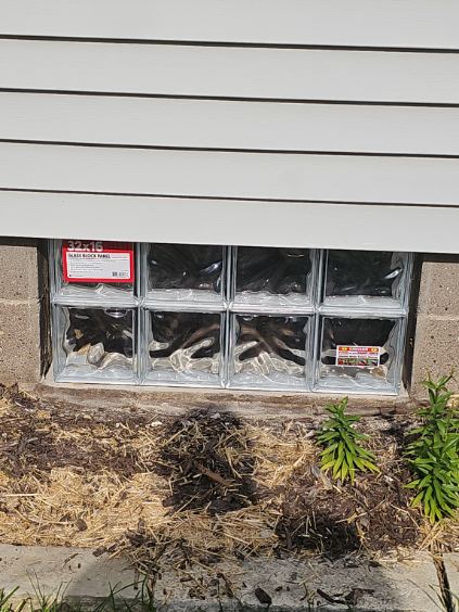 Newly installed mortar-set glass block basement window with the product label still attached