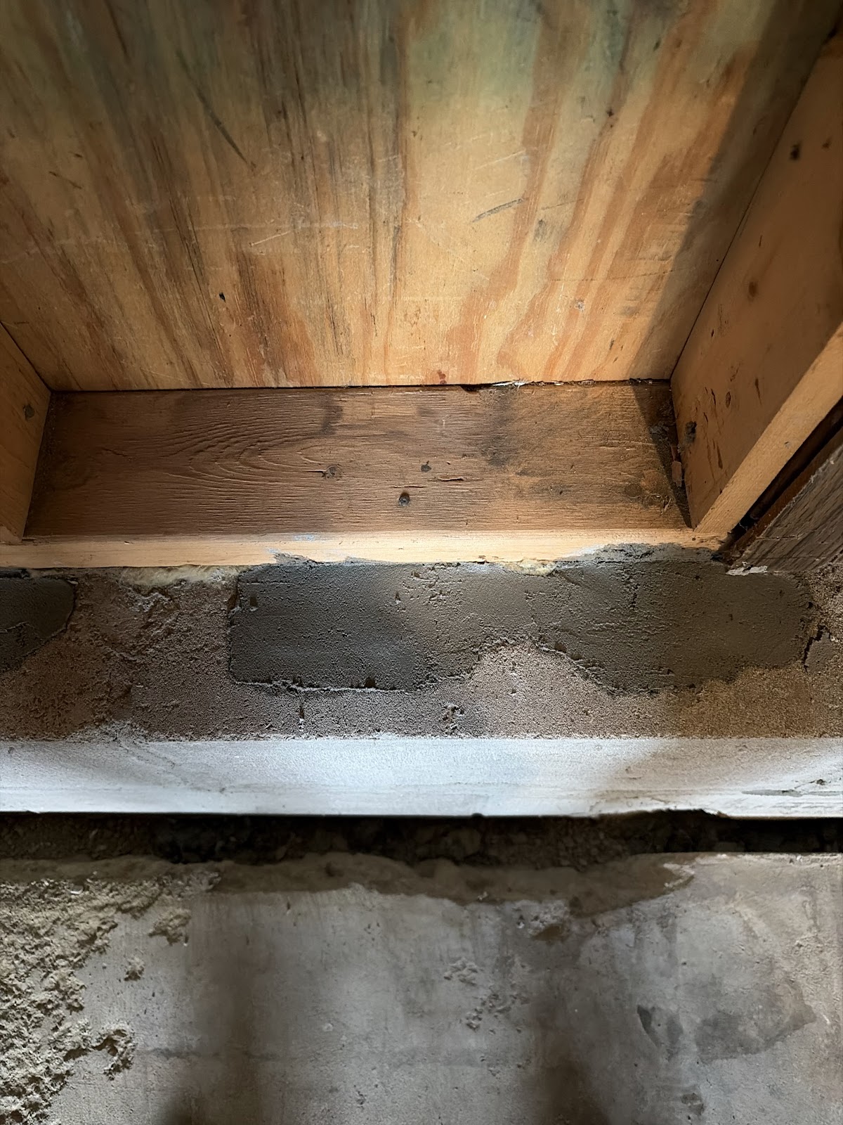 Fresh mortar and parging applied along the base of the block wall