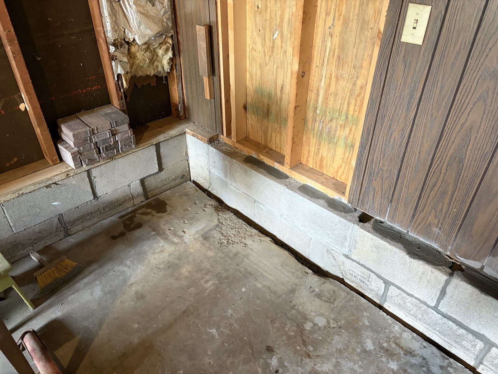 Repaired concrete block wall base at the garage corner after tuckpointing