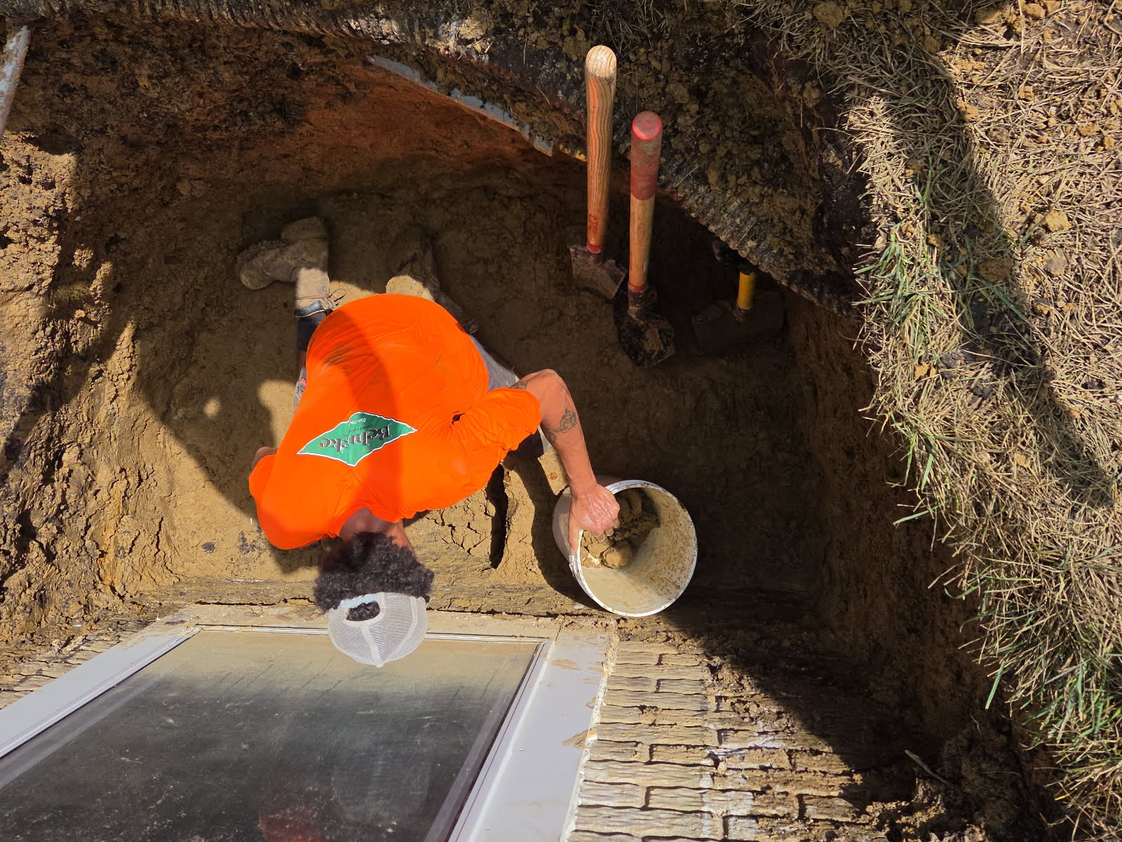Installing clean, free-draining drainage stone in the egress window well