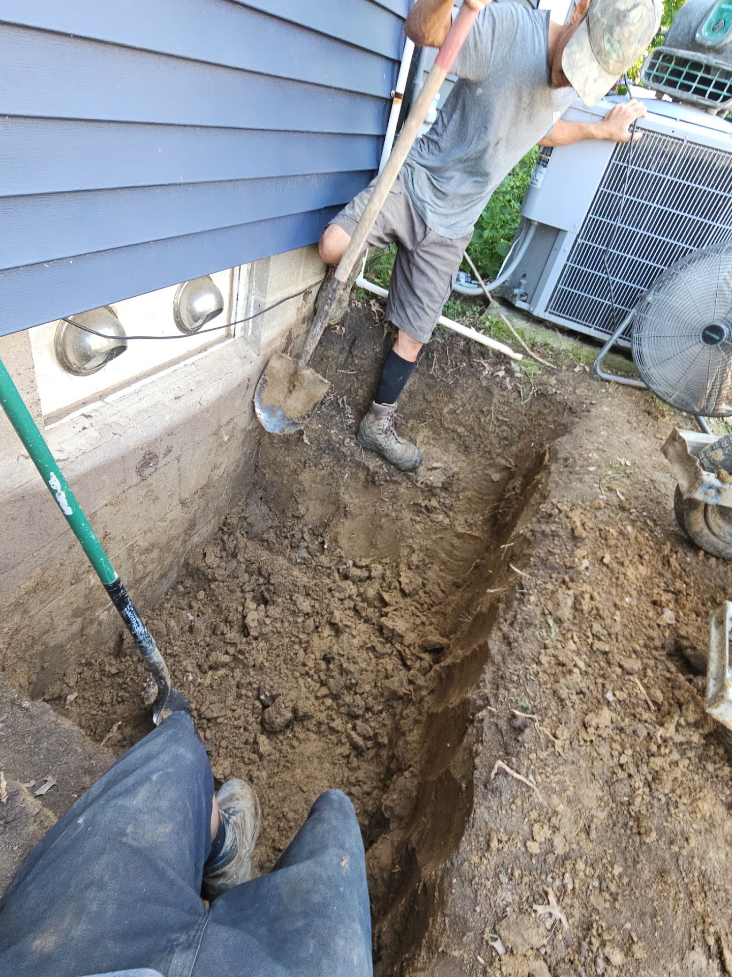 Excavated trench alongside the foundation for the new well and drainage