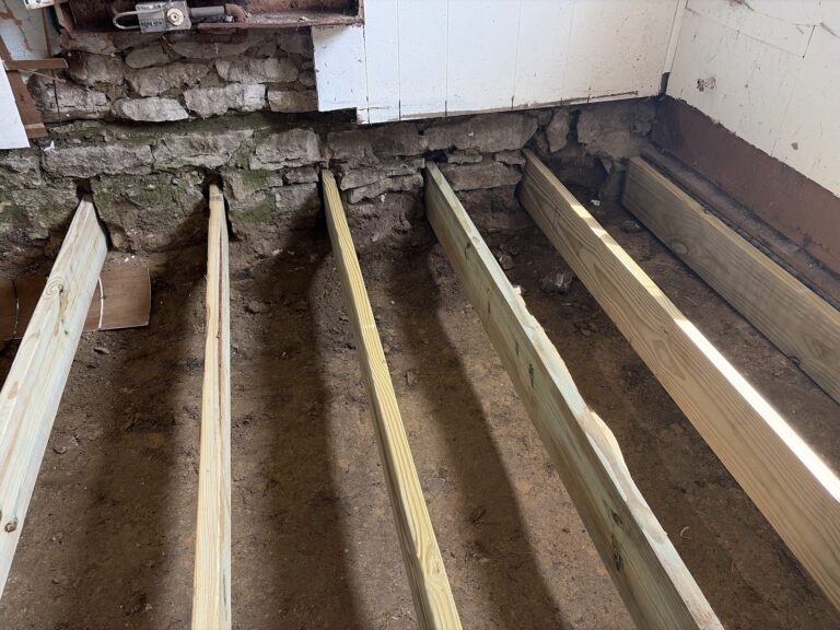 Rebuilt floor framing with new pressure-treated joists and center bearing support in a Davenport, Iowa home