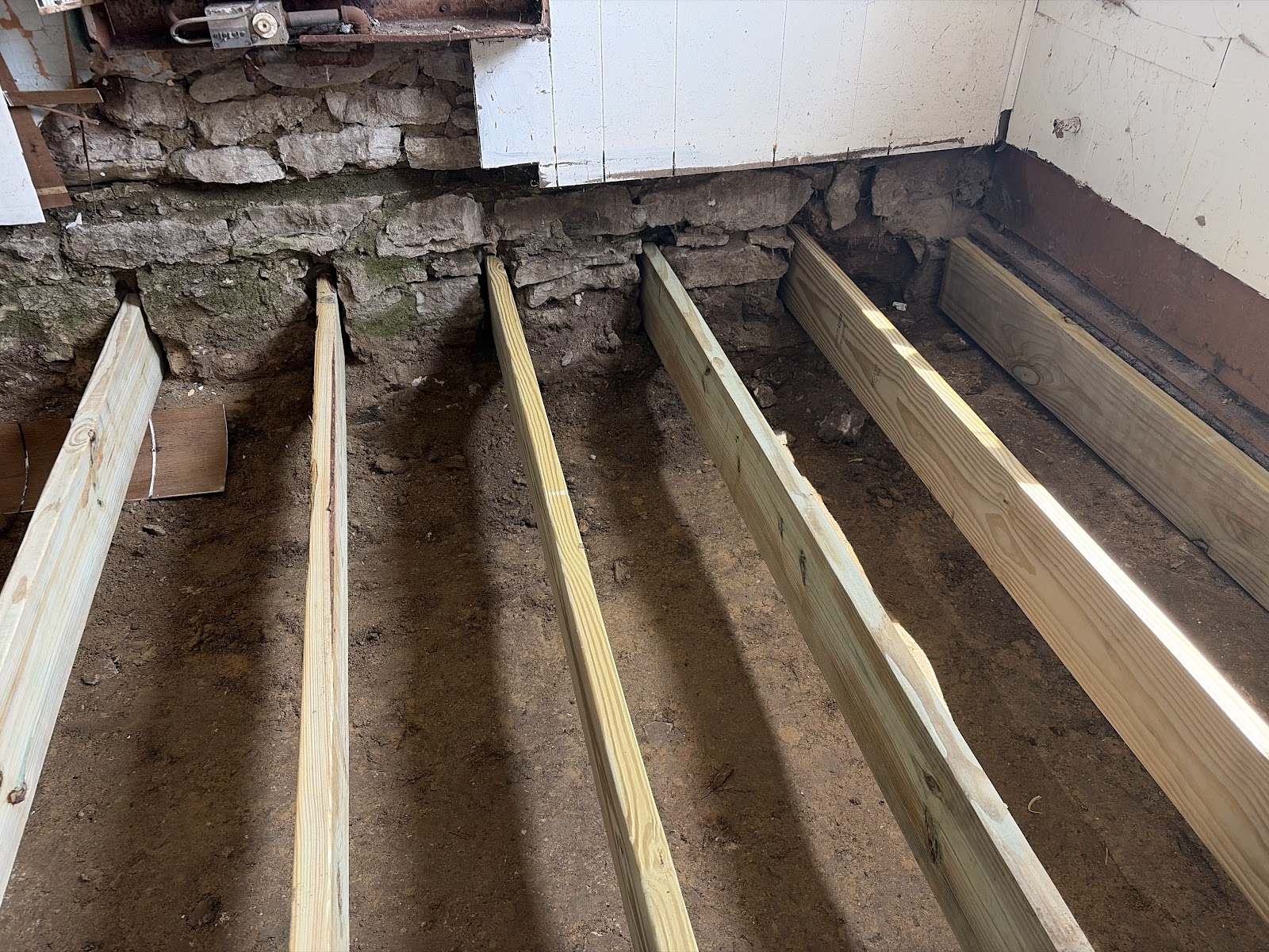 Rebuilt floor framing with new pressure-treated joists and center bearing support in a Davenport, Iowa home