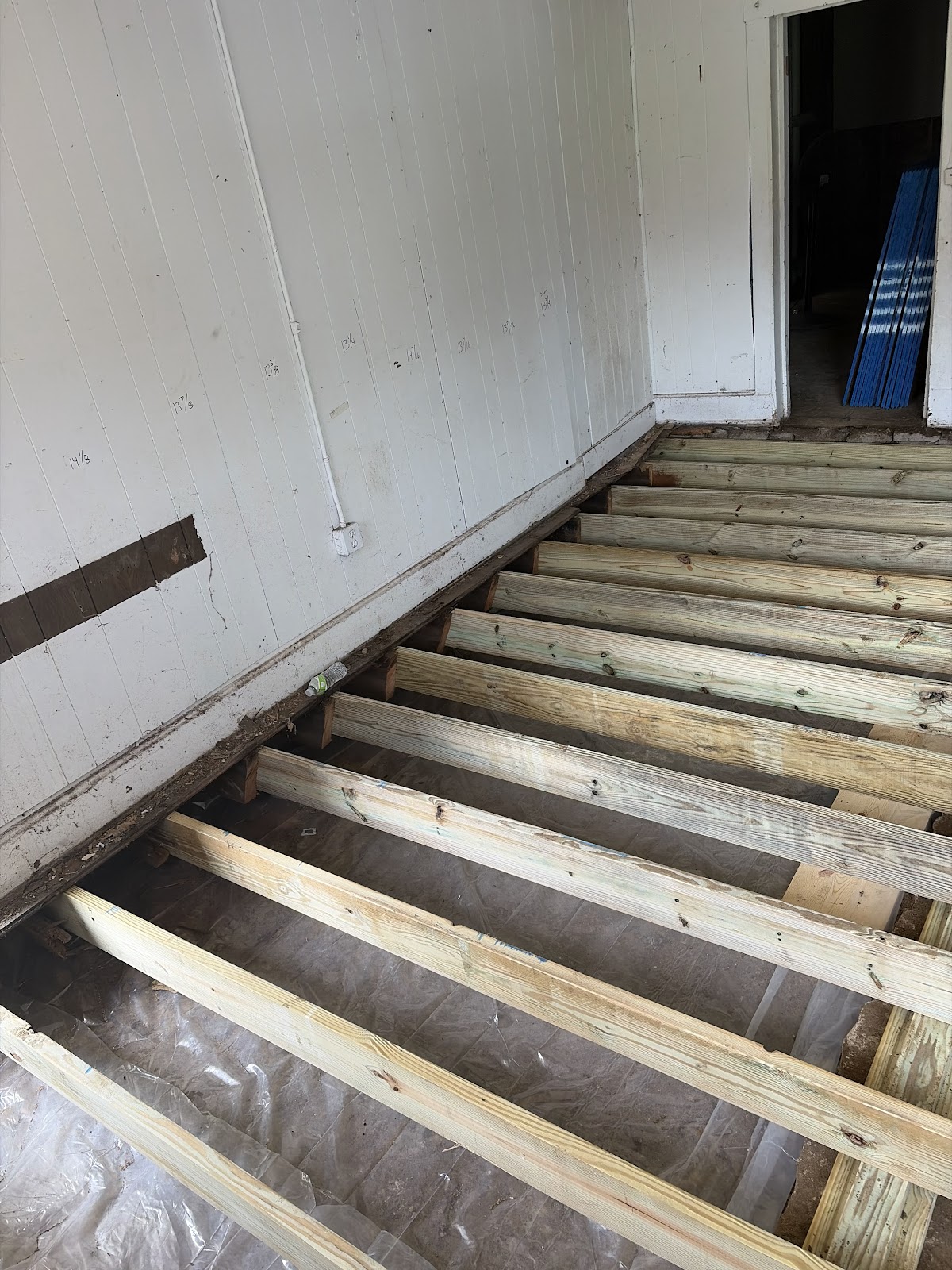 New pressure-treated floor joists spanning the rebuilt structural system