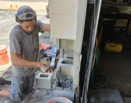 Mason installing replacement CMU block — project photo 4