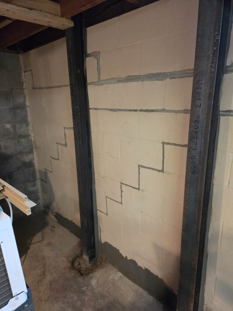 Steel I-beam wall brace installed against a bowing concrete block foundation wall in Taylor Ridge, Illinois