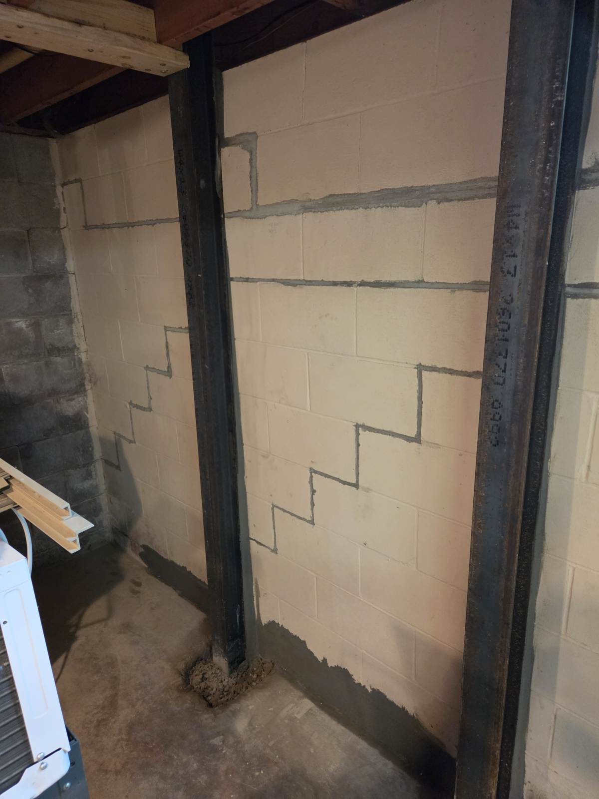 Steel I-beam wall brace installed against a bowing concrete block foundation wall in Taylor Ridge, Illinois