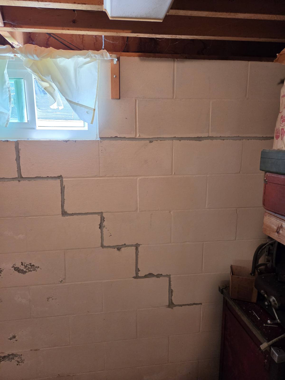 Stair-step cracking in a concrete block basement wall before bracing and tuckpointing