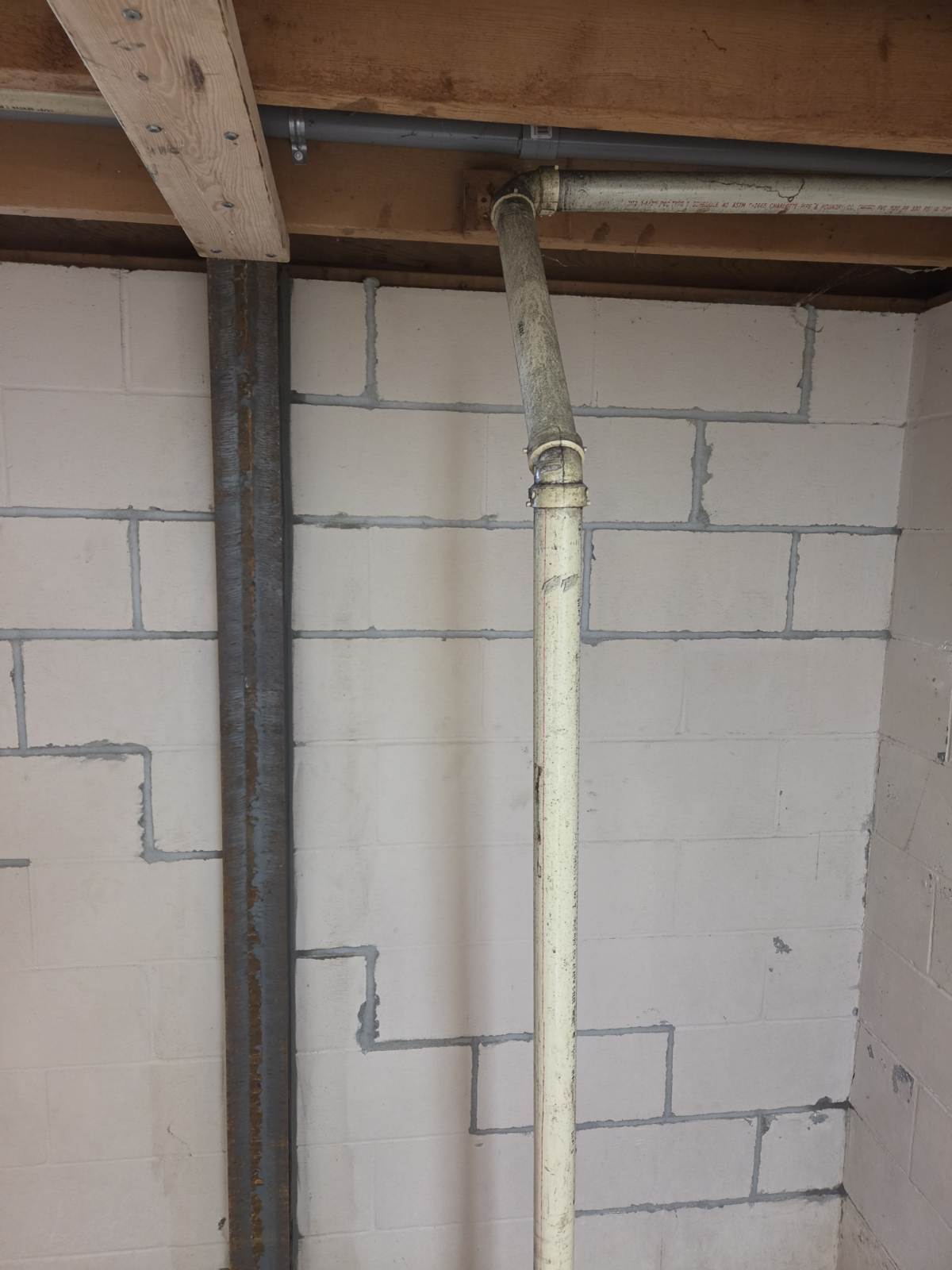 Vertical steel wall brace anchored along a block foundation wall