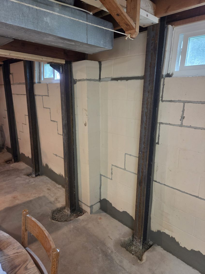 Close-up of a heavy-duty steel I-beam brace securing a basement foundation wall