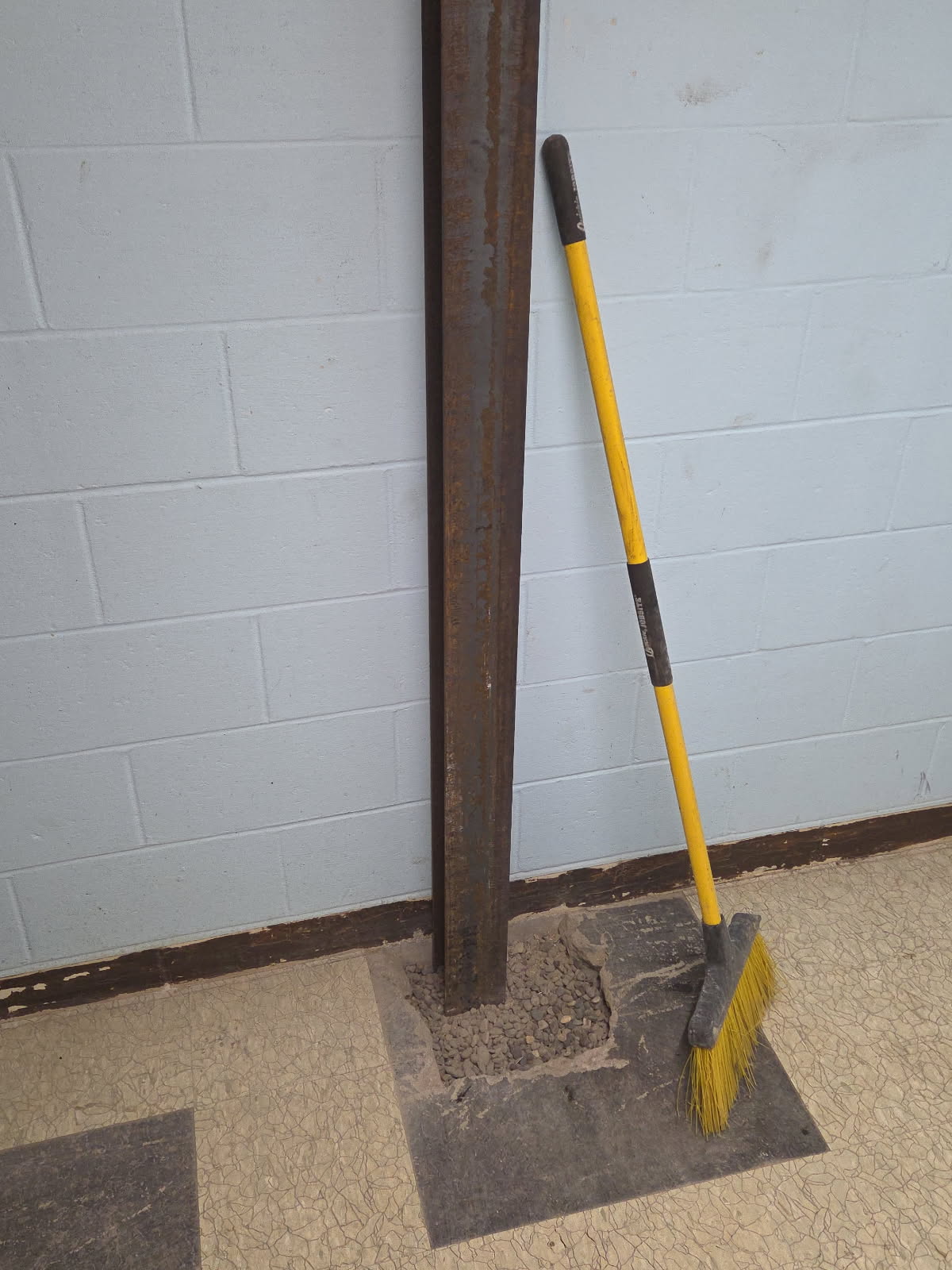 Steel bracing during installation, held with a strap and level against the foundation wall