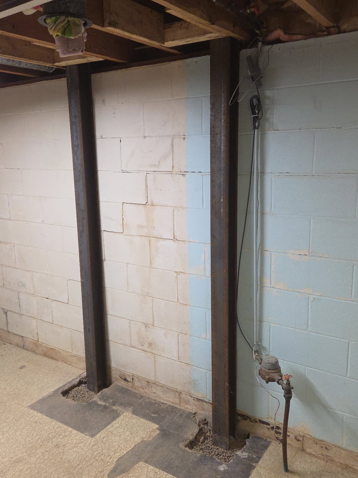 Heavy-duty steel I-beam bracing installed along the foundation wall