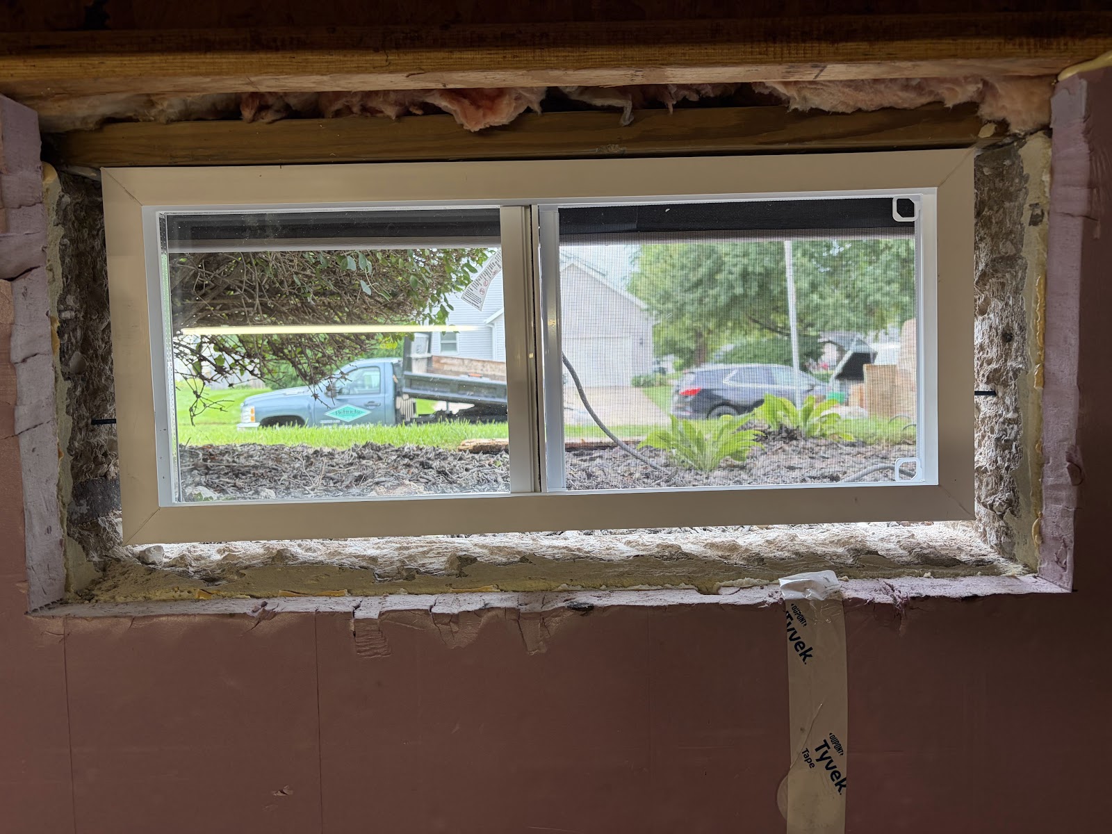 New double-sliding basement window from inside showing the sealed perimeter and framing