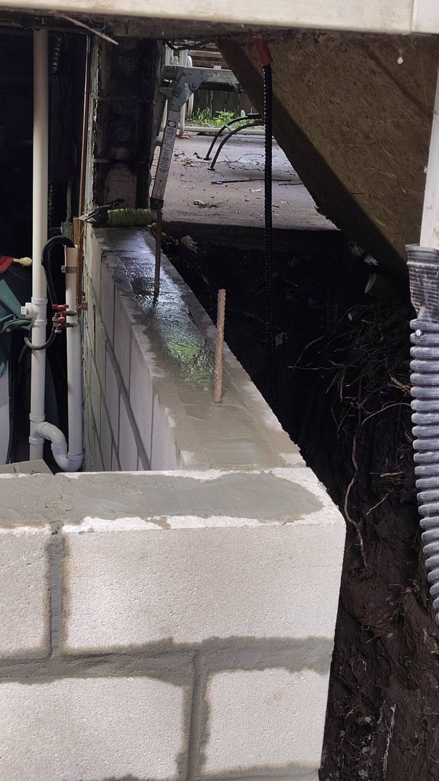 New block course with fresh mortar and a temporary shoring post carrying the structure above