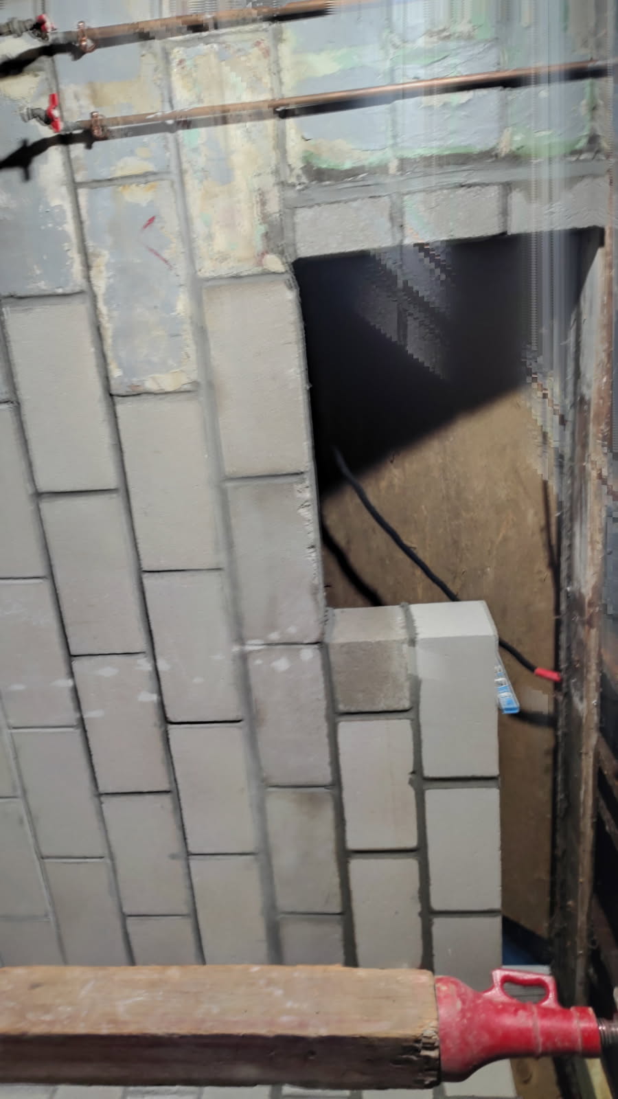 Interior view of the rebuilt block foundation wall showing new courses and an opening