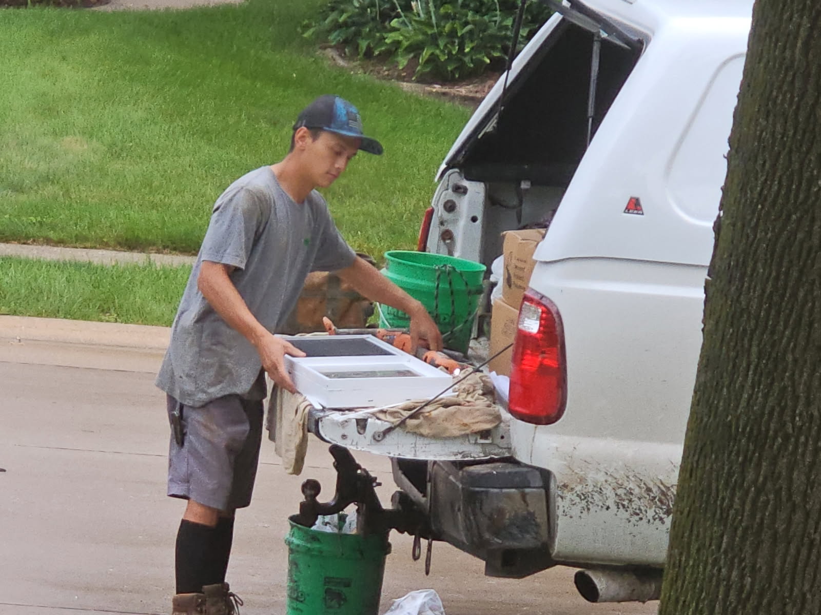 Crew member carrying a new basement window unit from the work truck