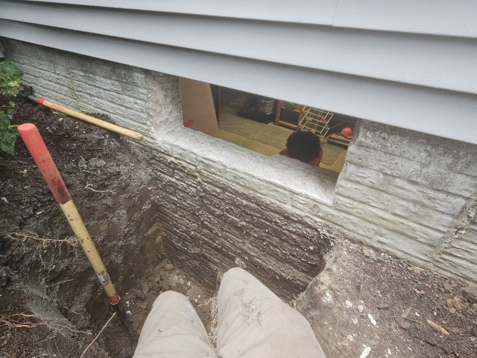 Tamping tool resting on the backfilled soil alongside the foundation