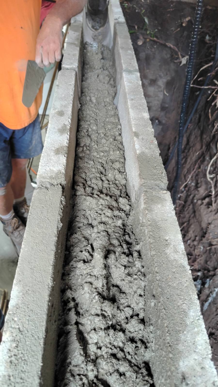 Bond beam block course filled with fresh grout, with reinforcing steel running through it