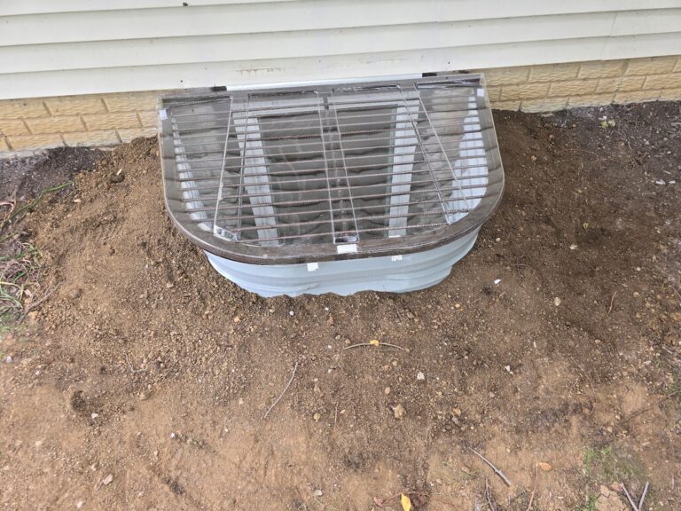 Completed egress window well with protective grate on a Davenport, Iowa home