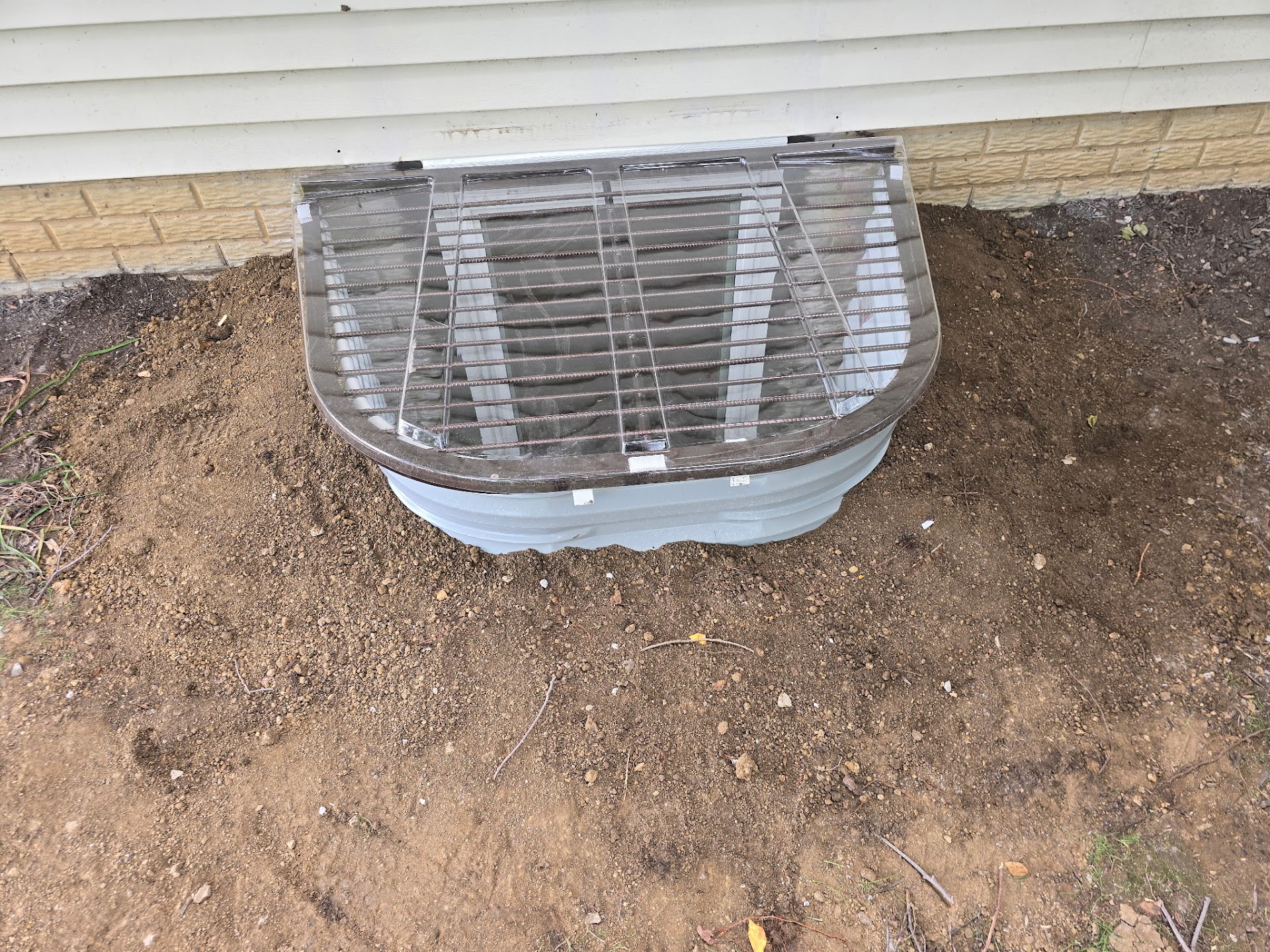 Completed egress window well with protective grate on a Davenport, Iowa home