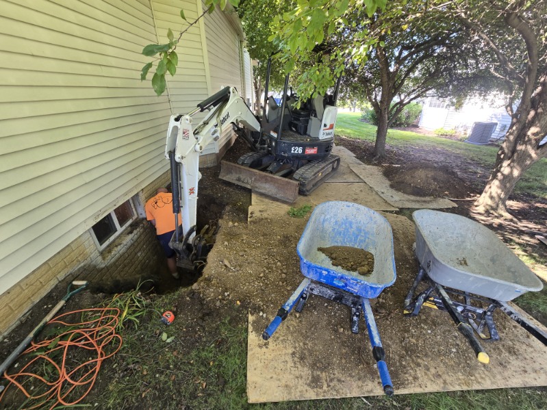 Crew excavating along the poured concrete foundation to install an egress window