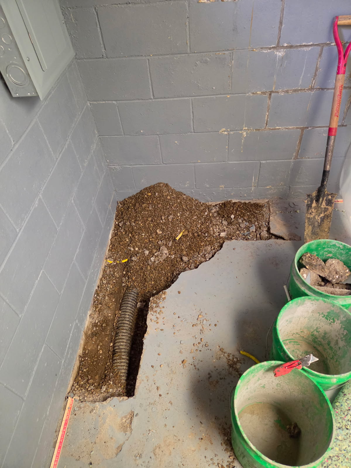Basement floor opened along the wall exposing the damaged drain tile area