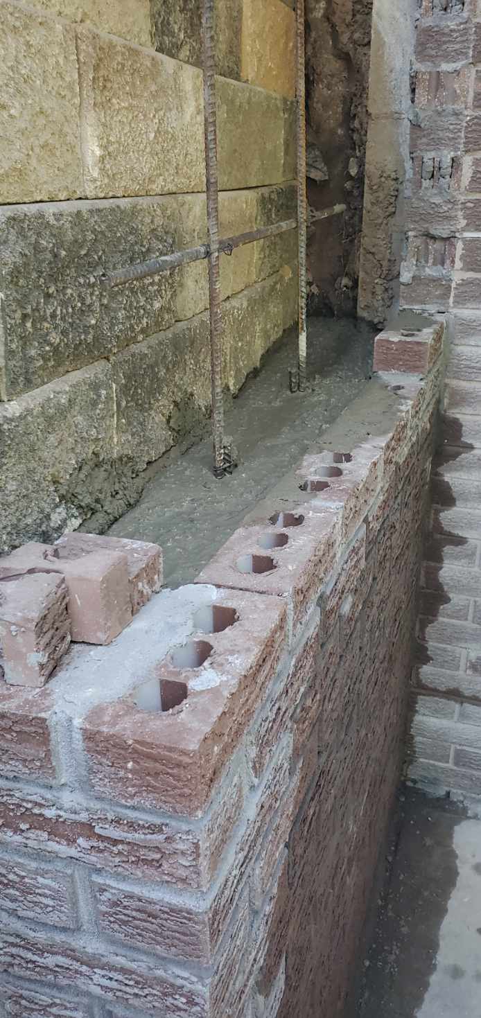 Block and brick being laid for the rebuilt retaining wall section