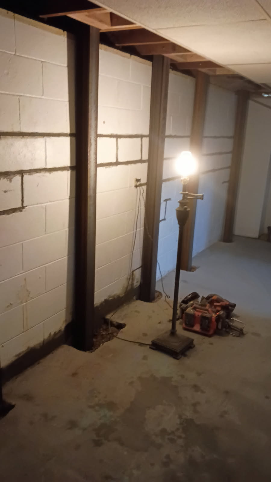 Steel I-beam brace set tight against the block wall with repaired mortar joints