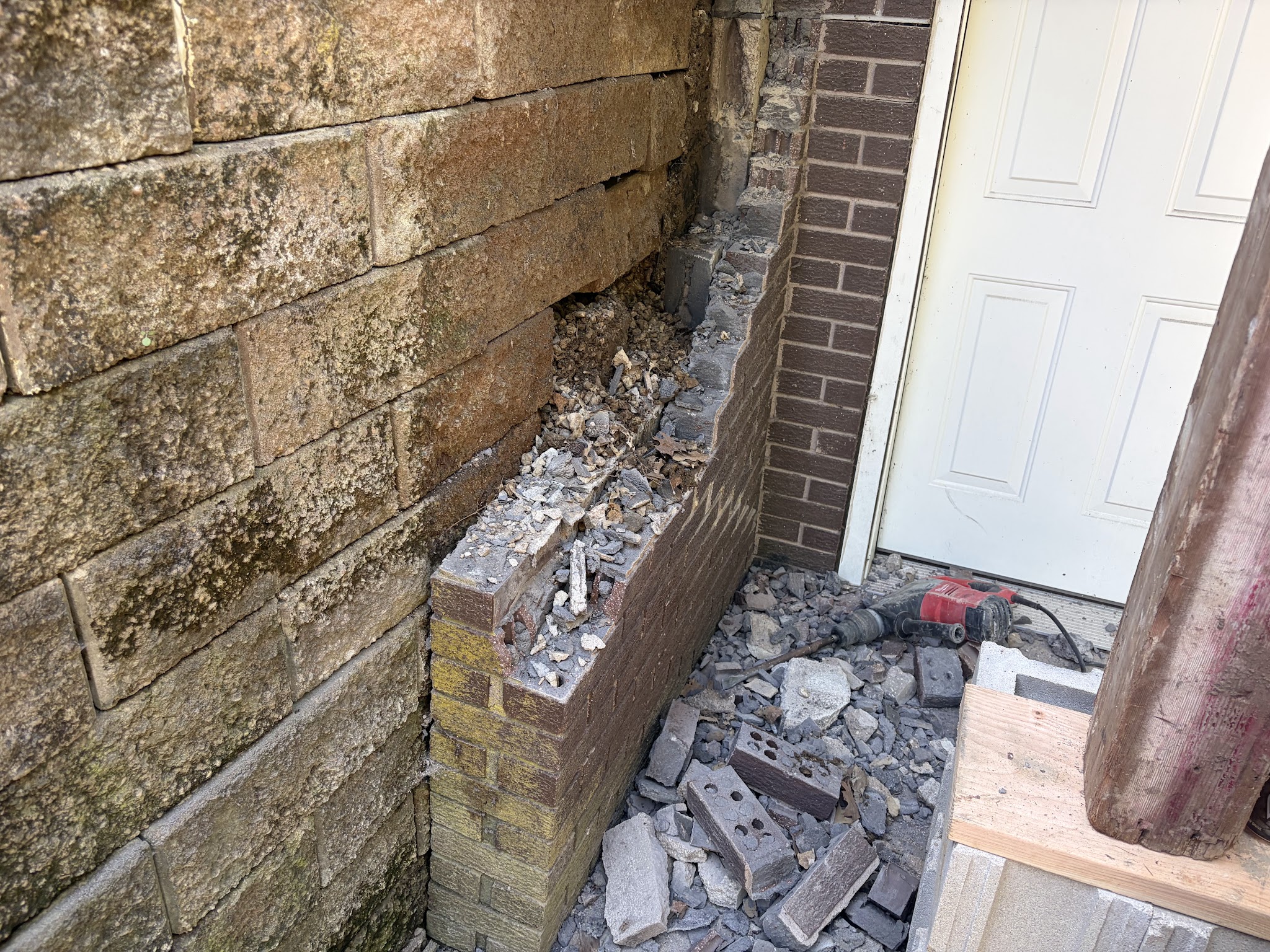 Damaged brick support wall pushed out by the failing retaining wall before repair