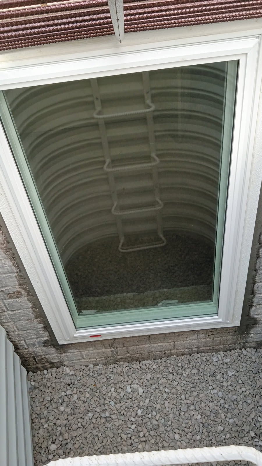 New egress window looking out into the well with ladder and gravel floor, Bettendorf