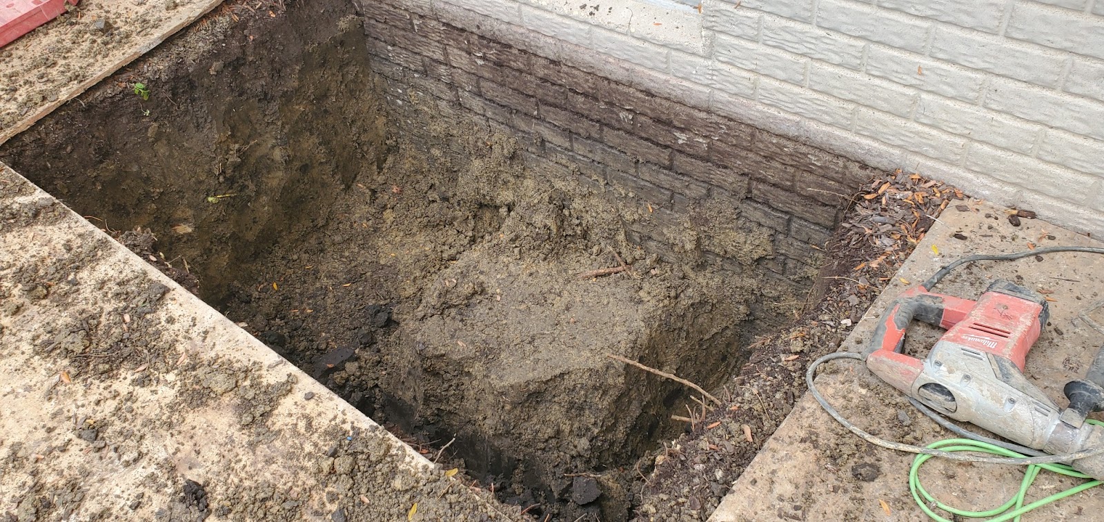 Excavation for a new egress window well against a poured foundation wall in Bettendorf