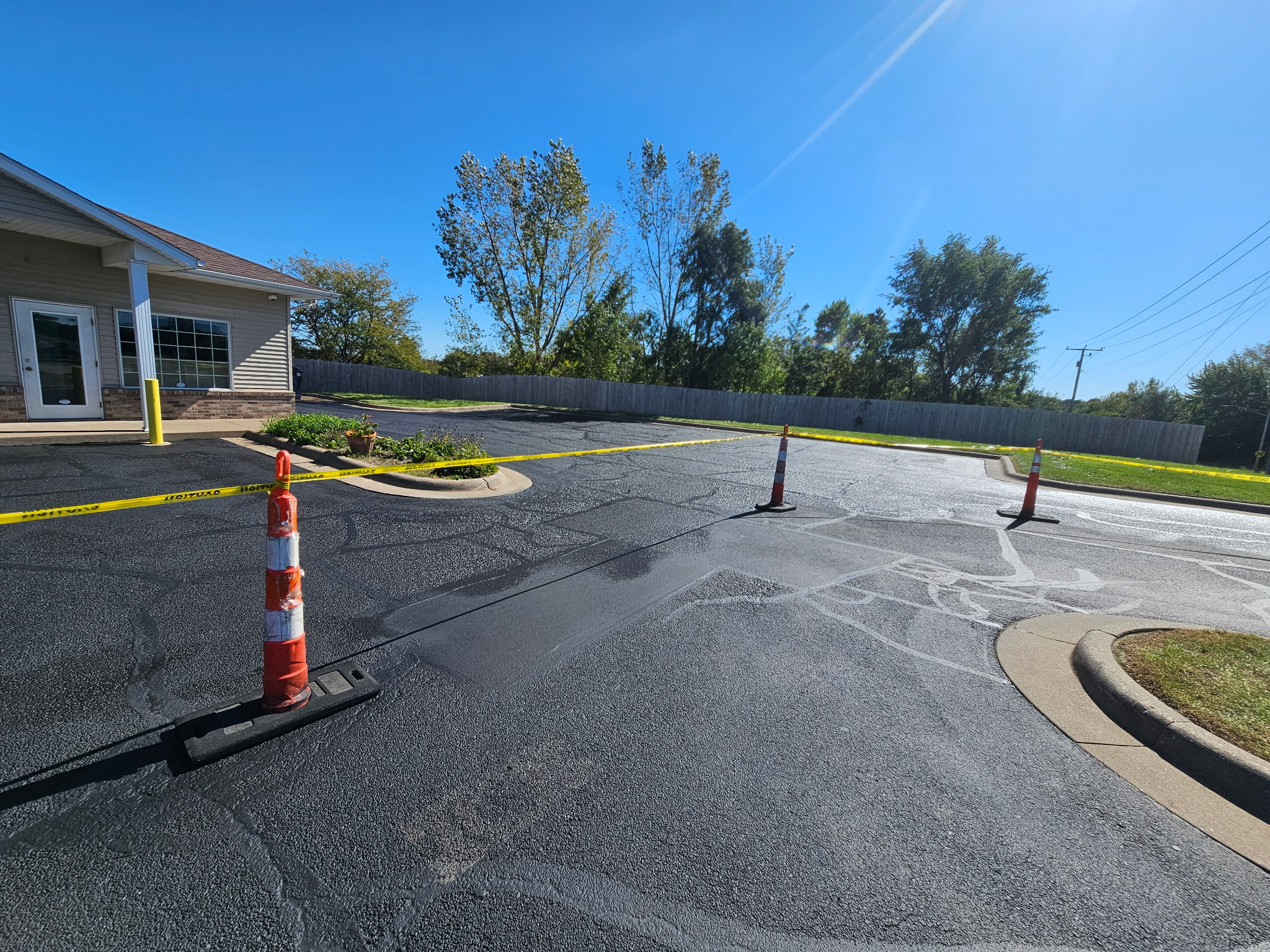Freshly sealcoated parking lot in front of a Davenport business with cones and caution tape