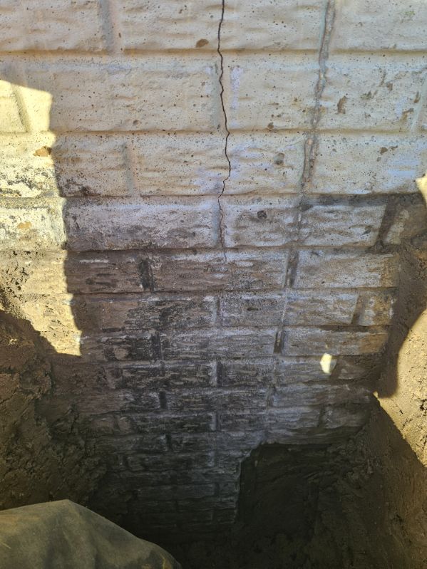 Settlement crack in the block foundation wall seen from the exterior excavation