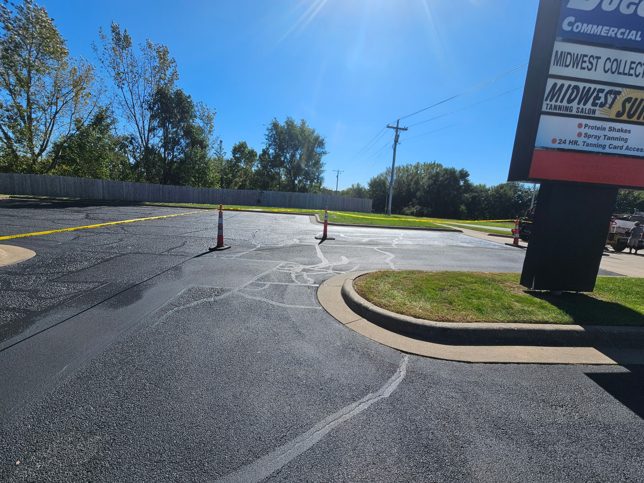 Cracked asphalt parking lot in Davenport with traffic cones set out before sealcoating
