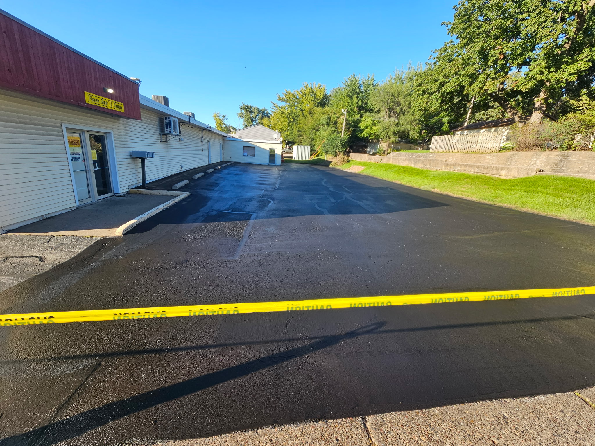 Freshly sealcoated parking lot at Popcorn Charlie's in Davenport, taped off while the sealer cures
