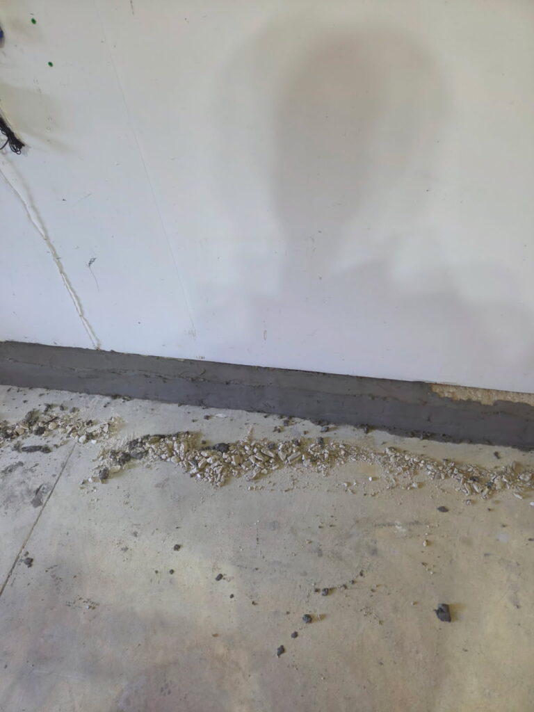 Repaired garage stem wall with a smooth new bonded surface along the floor in Moline