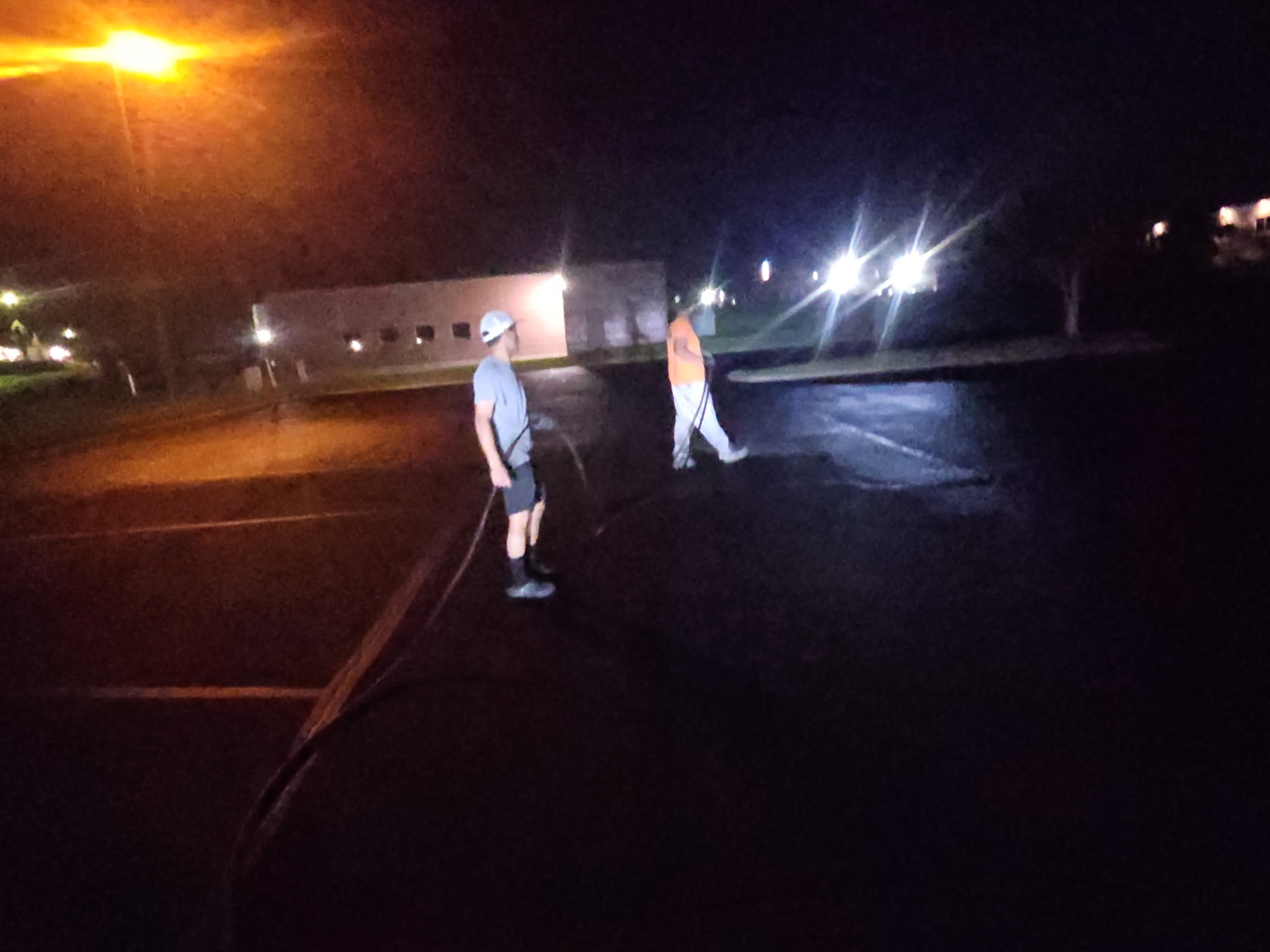 Crew finishing the sealcoating on the Bettendorf parking lot after dark under the lot lights