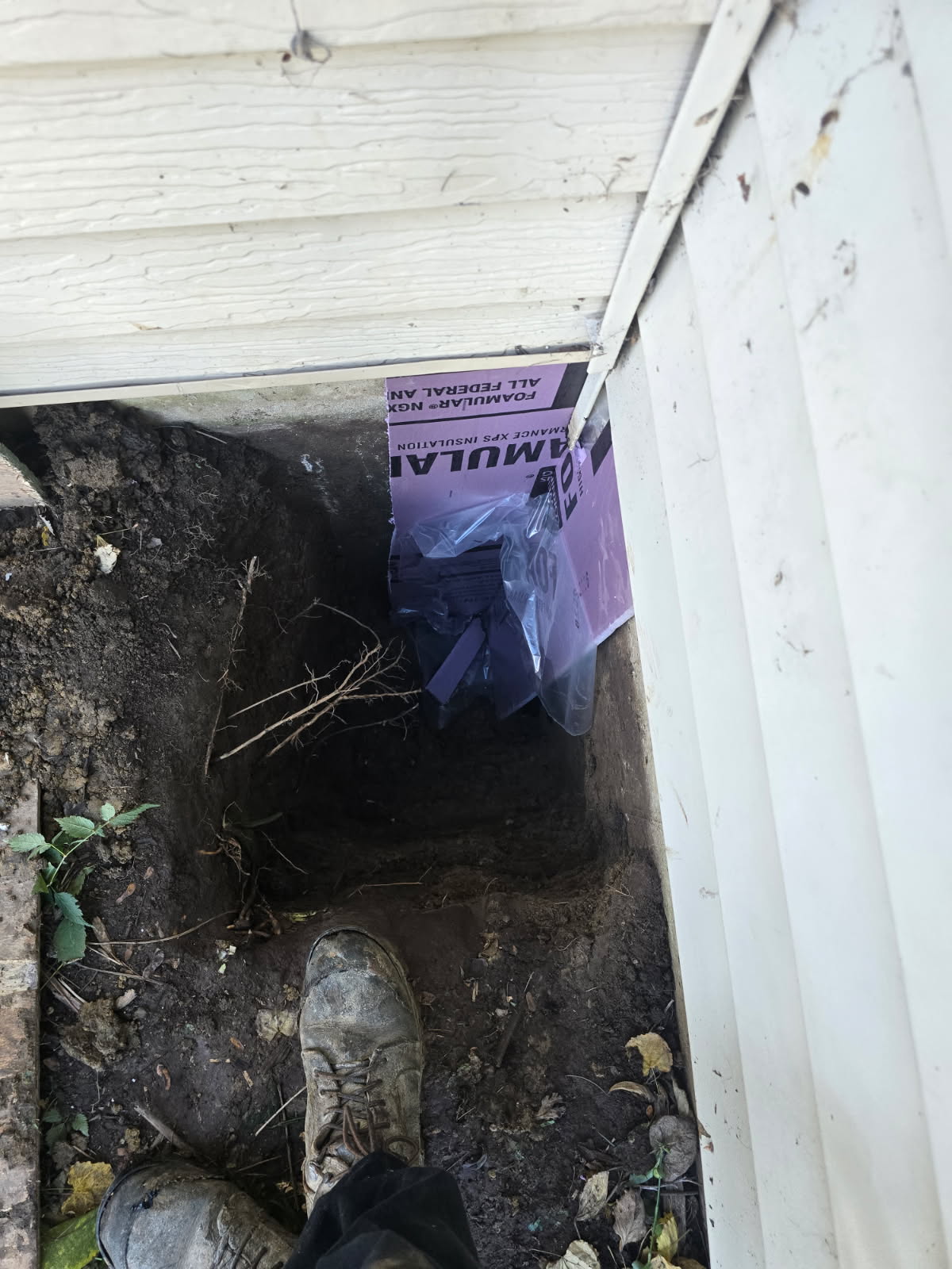 Protective sheeting placed against an exposed foundation wall in Moline