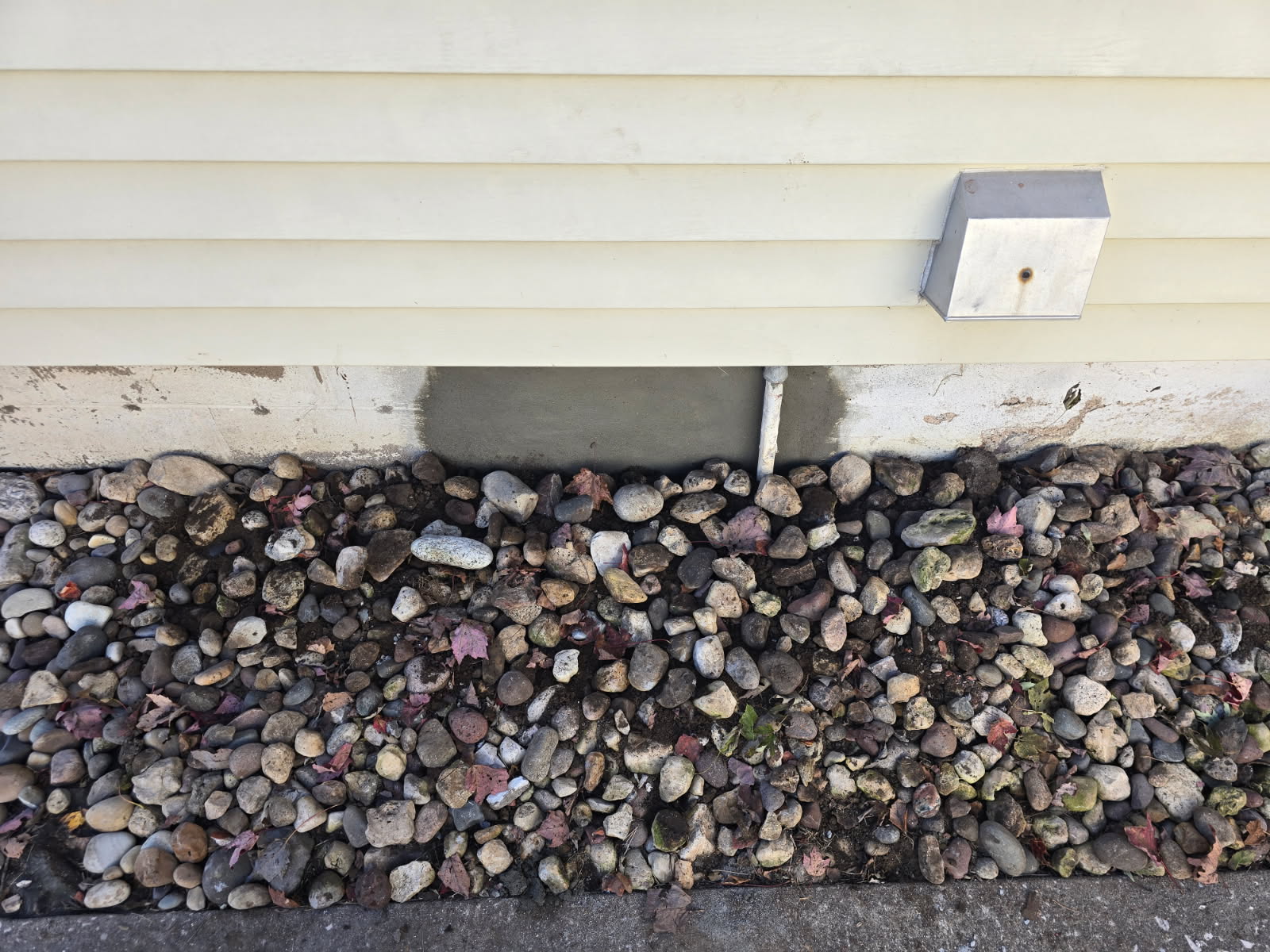 Repaired foundation parging above a rock bed at a Moline home