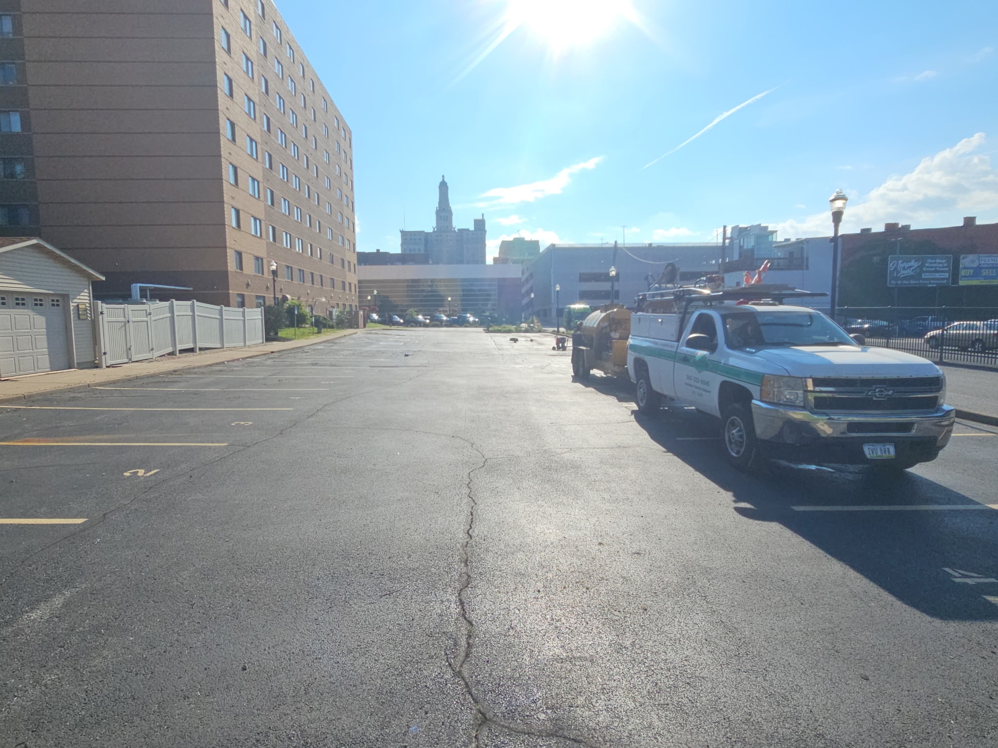 Downtown Davenport parking lot with the Behncke crew truck and sealcoating rig, tall buildings behind