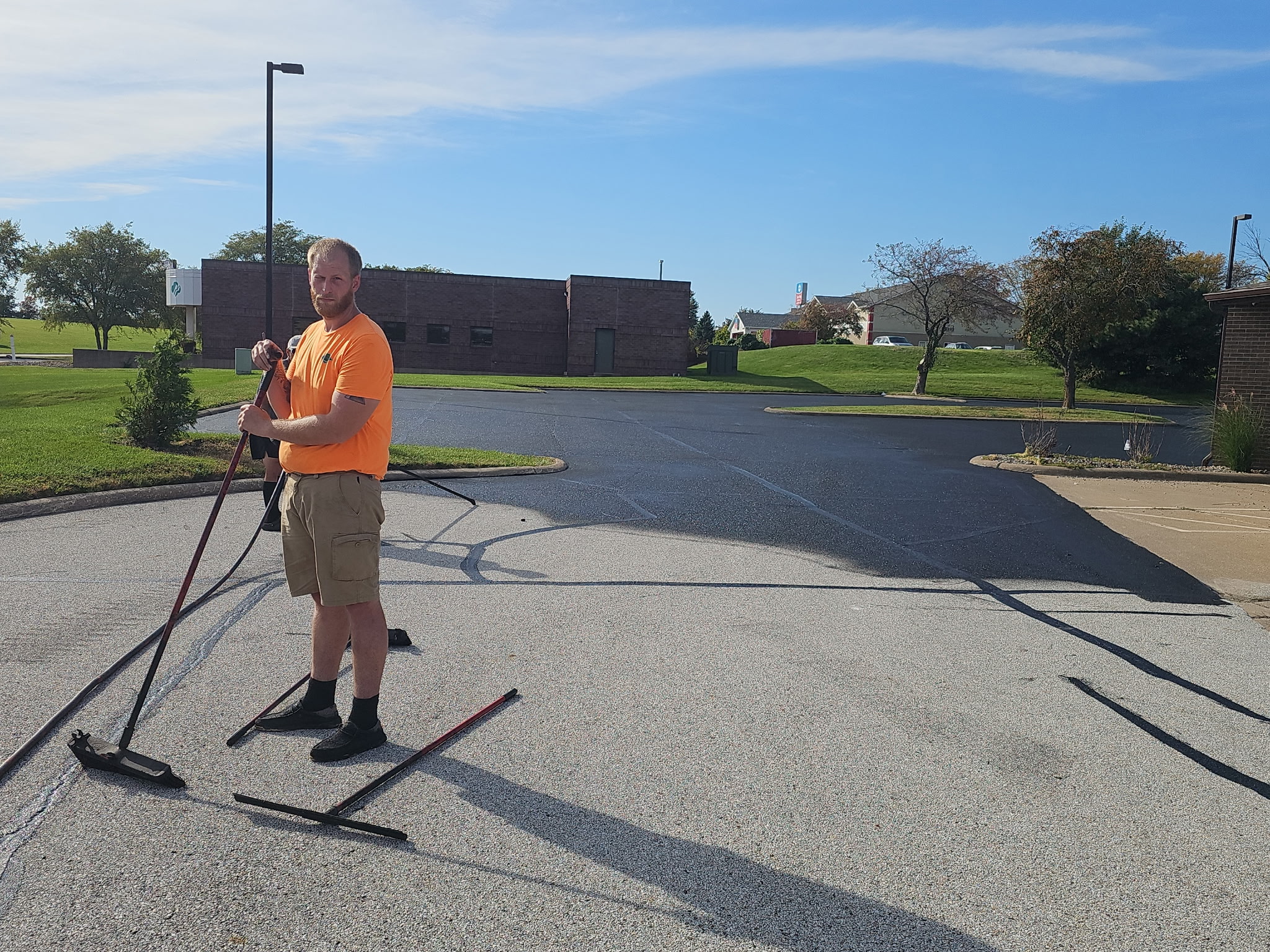 Crew member with a squeegee working sealer along the Bettendorf parking lot
