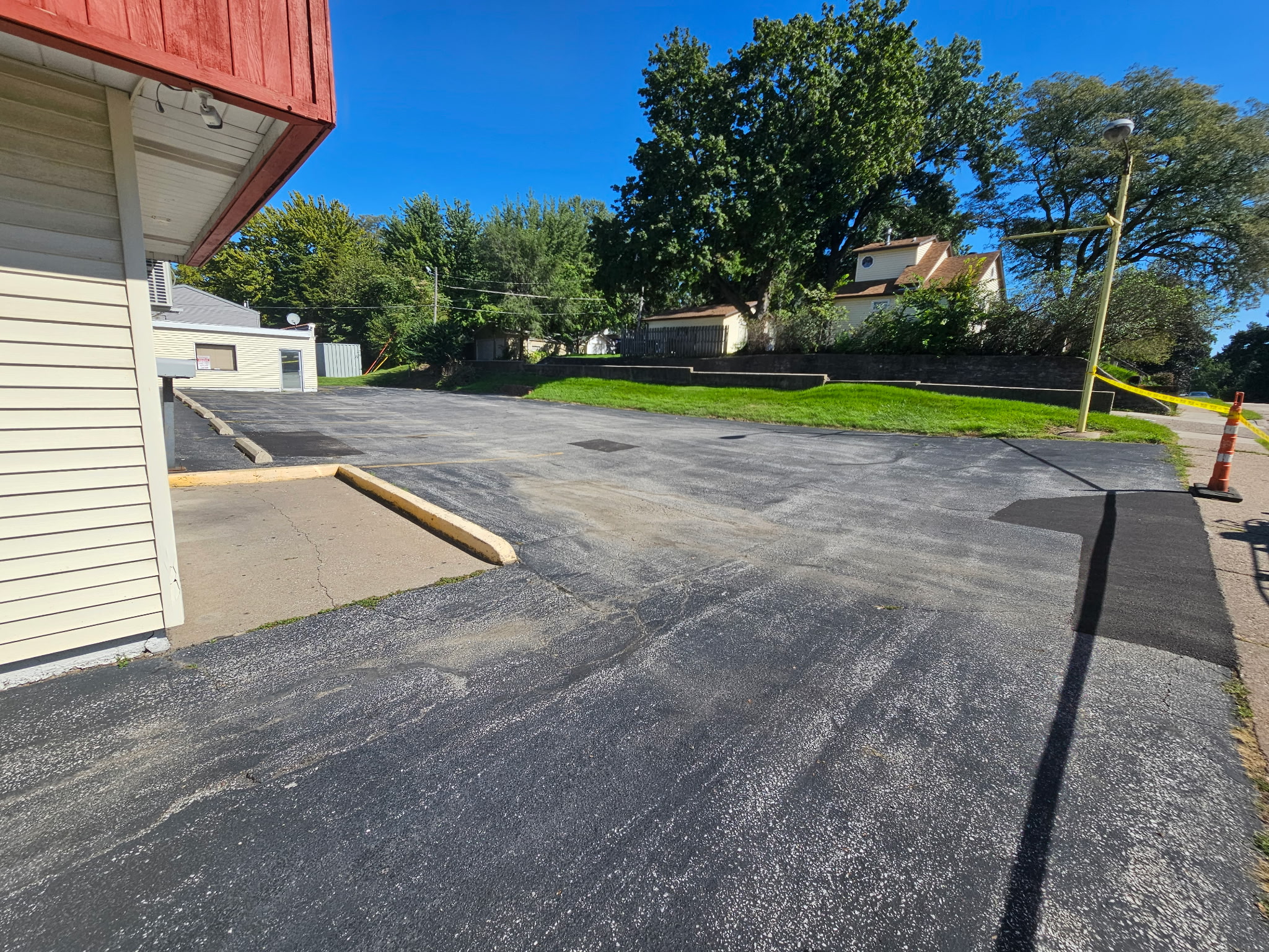 Freshly sealed black asphalt at Popcorn Charlie's with trees in the background