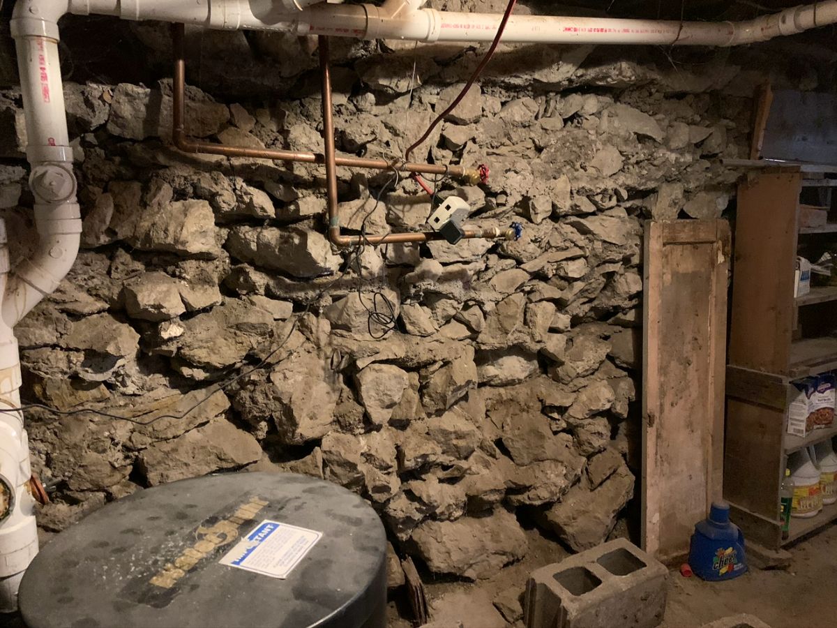 A rubble stone basement wall that has lost much of its mortar. The stones are still sound.